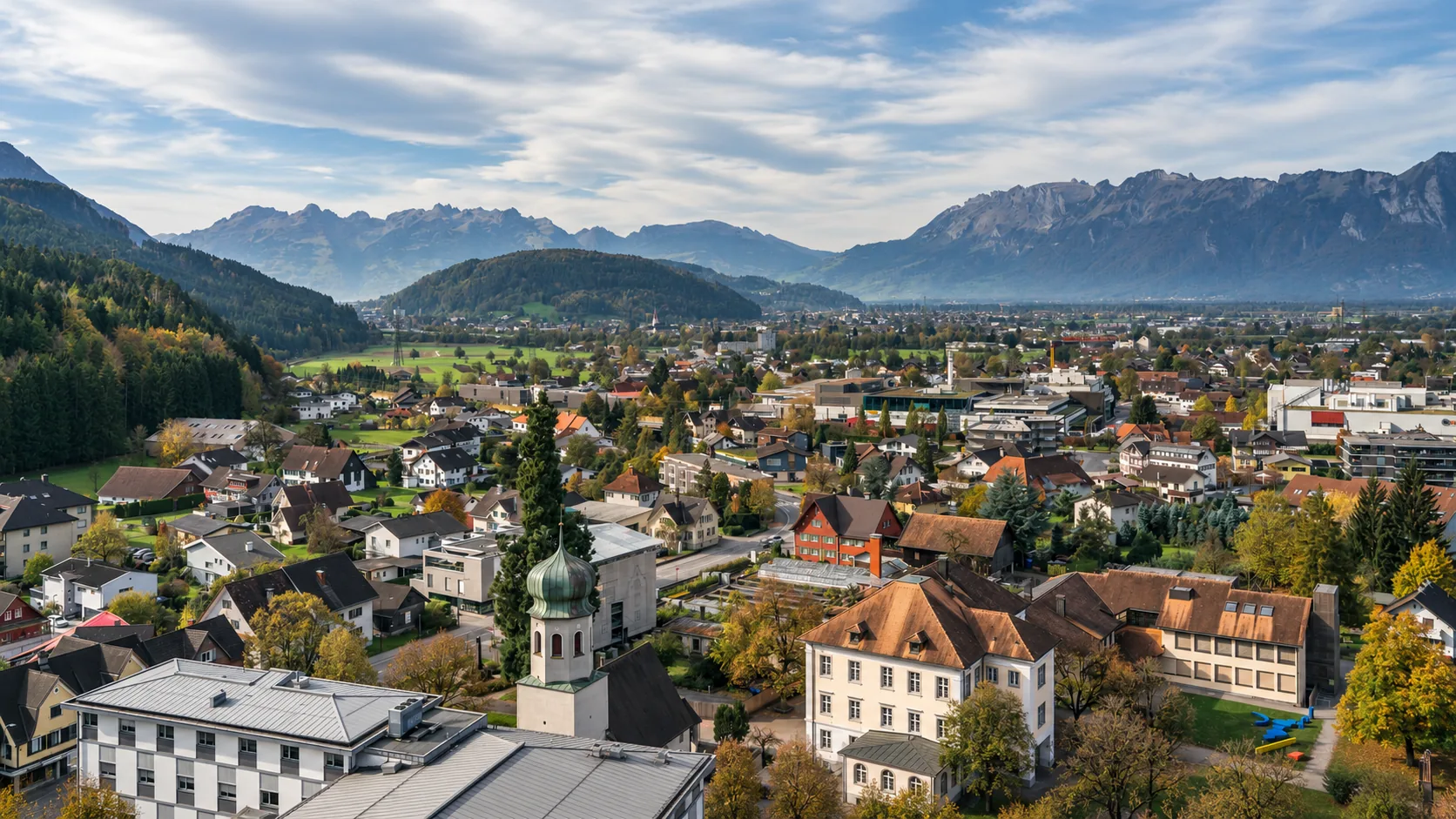 Alpine town with industry among homes, fields and mountains